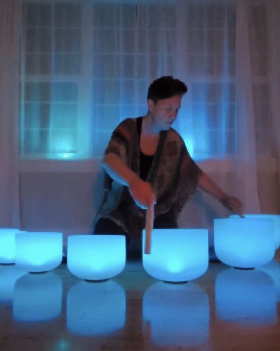 Melody playing glowing crystal singing bowls during a sound bath